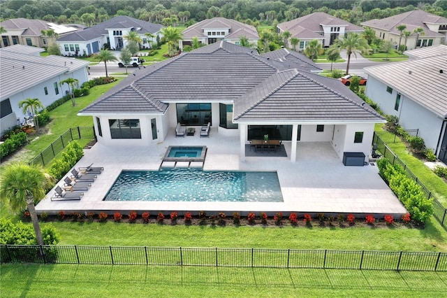 rear view of house with outdoor lounge area, a yard, a patio, and a pool with hot tub