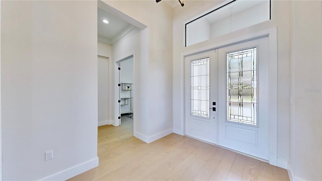 foyer featuring french doors, light hardwood / wood-style floors, and ornamental molding