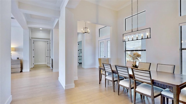 dining space featuring light hardwood / wood-style flooring, beamed ceiling, and an inviting chandelier