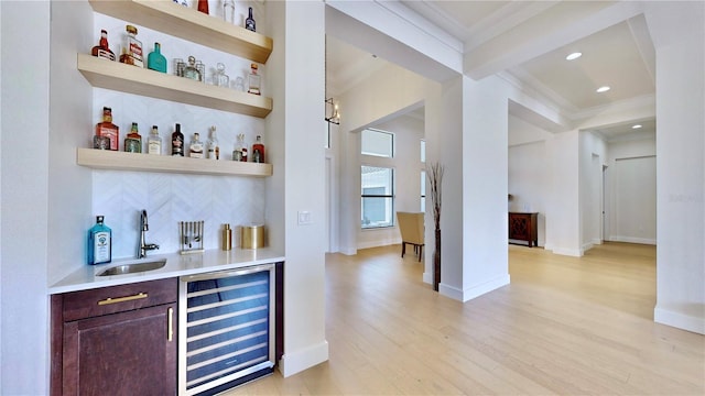 bar with light wood-type flooring, tasteful backsplash, sink, beam ceiling, and wine cooler