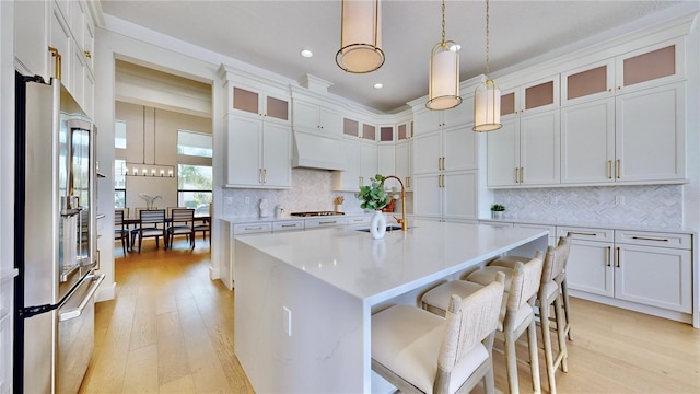 kitchen with white cabinetry, an island with sink, stainless steel appliances, and custom exhaust hood