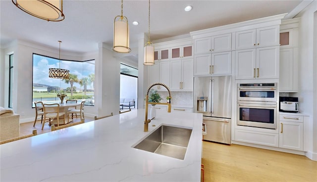 kitchen with appliances with stainless steel finishes, white cabinetry, pendant lighting, and sink