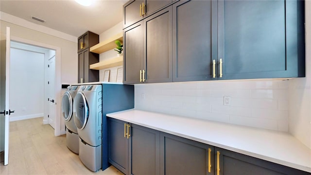 laundry area with cabinets, washing machine and dryer, and light hardwood / wood-style floors