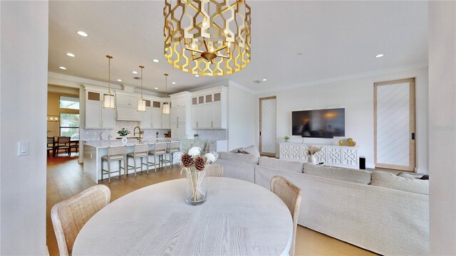 dining space featuring sink, crown molding, and light hardwood / wood-style flooring