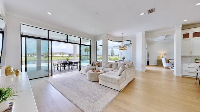 living room with an inviting chandelier, a healthy amount of sunlight, and light hardwood / wood-style floors