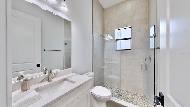 bathroom featuring vanity, a shower with shower door, and toilet