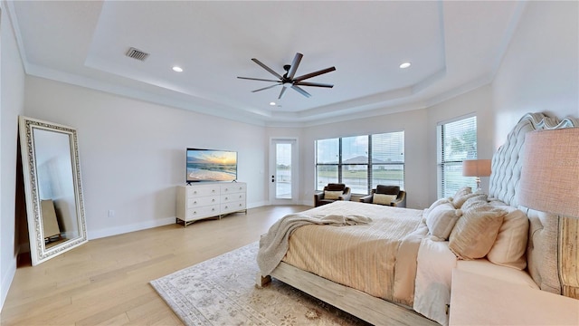 bedroom featuring light wood-type flooring, a tray ceiling, and ceiling fan