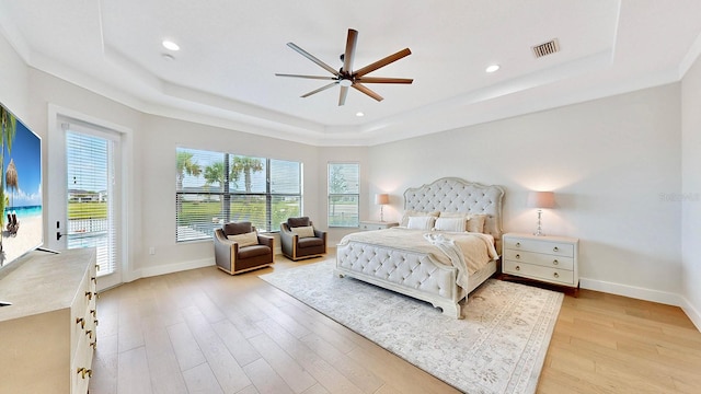 bedroom featuring access to exterior, light hardwood / wood-style floors, a raised ceiling, and ceiling fan