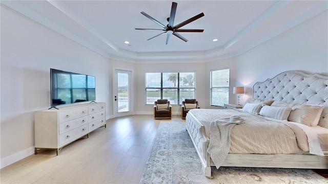 bedroom featuring ceiling fan, light hardwood / wood-style floors, access to outside, and a tray ceiling