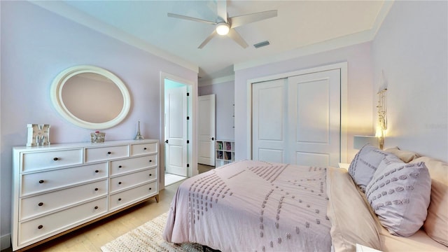 bedroom featuring ceiling fan, light hardwood / wood-style floors, ornamental molding, and a closet