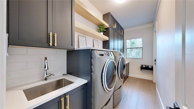 laundry room featuring sink, cabinets, light wood-type flooring, and independent washer and dryer