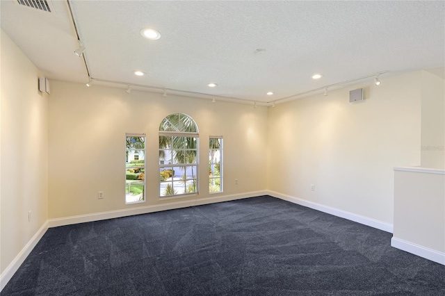 carpeted empty room featuring rail lighting and a textured ceiling