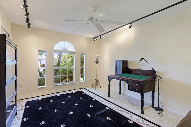 interior space featuring ceiling fan, rail lighting, and a textured ceiling