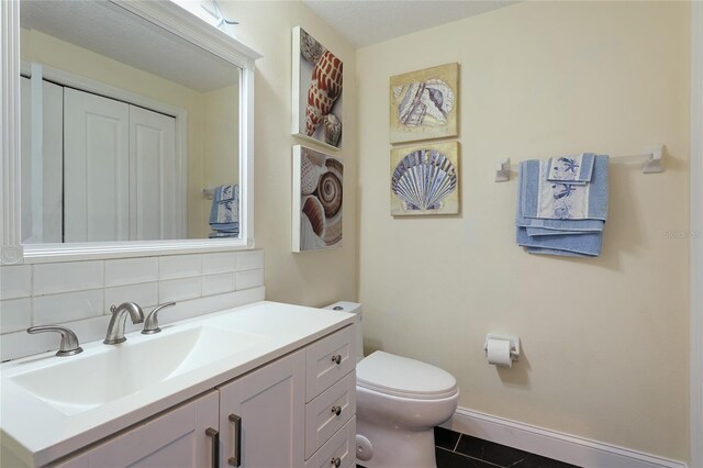 8607 51st Ave W, Bradenton, FL 34210 - bathroom with toilet, tasteful backsplash, vanity, tile patterned floors, and baseboards