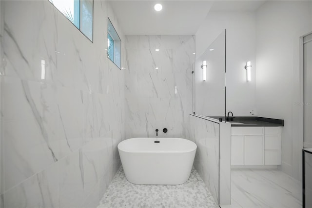 bathroom featuring a bathing tub, vanity, and tile walls