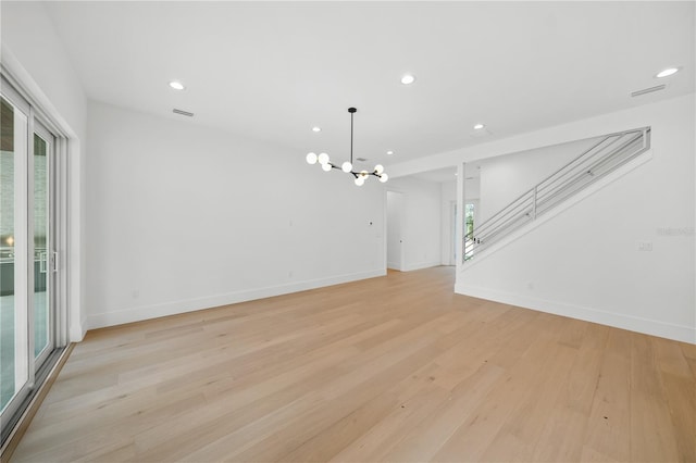 unfurnished living room featuring a chandelier, a healthy amount of sunlight, and light wood-type flooring