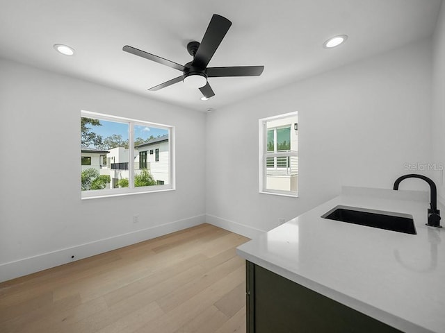 interior space with ceiling fan, sink, and light wood-type flooring