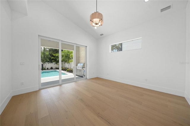 empty room featuring light hardwood / wood-style flooring and high vaulted ceiling