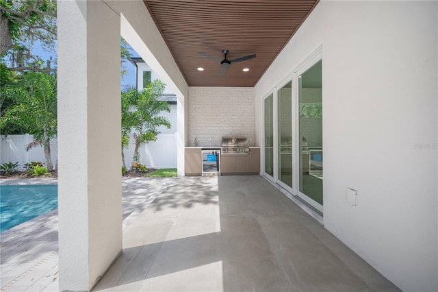 view of patio with ceiling fan, exterior kitchen, grilling area, a fenced in pool, and wine cooler