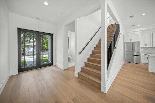 entrance foyer with french doors and light hardwood / wood-style flooring