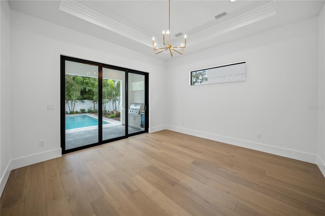 unfurnished room with hardwood / wood-style floors, an inviting chandelier, crown molding, and a tray ceiling