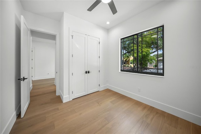 unfurnished bedroom featuring a closet, light hardwood / wood-style flooring, and ceiling fan