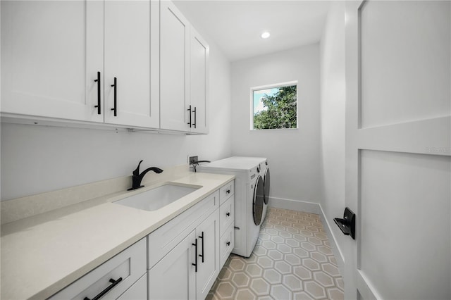 clothes washing area with cabinets, light tile patterned floors, separate washer and dryer, and sink