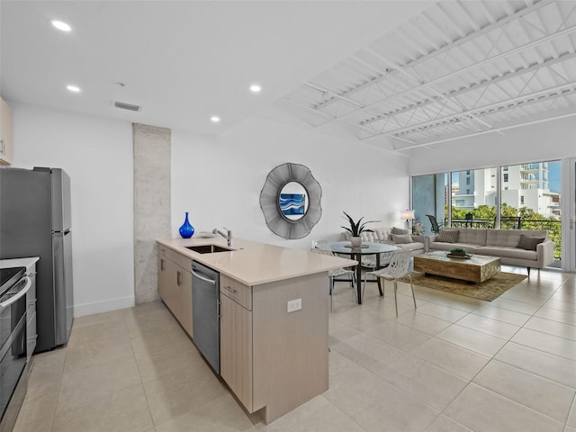 kitchen featuring sink, light brown cabinets, stainless steel appliances, kitchen peninsula, and light tile patterned floors