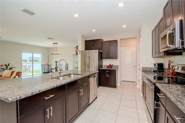 kitchen featuring sink, an island with sink, stainless steel appliances, light tile patterned floors, and dark brown cabinets