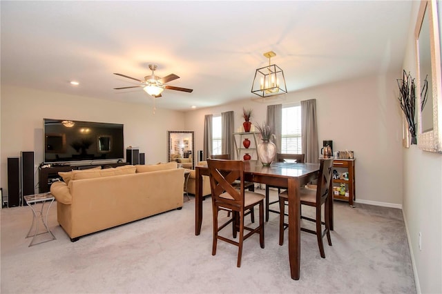 carpeted dining space featuring ceiling fan with notable chandelier