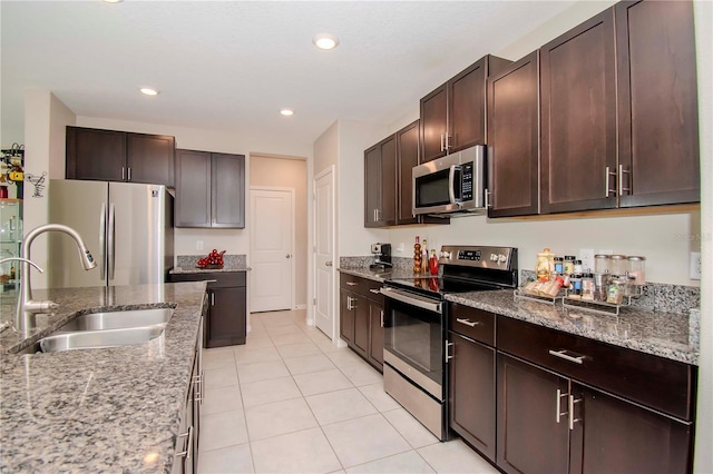 kitchen featuring light tile patterned floors, stainless steel appliances, light stone counters, and sink