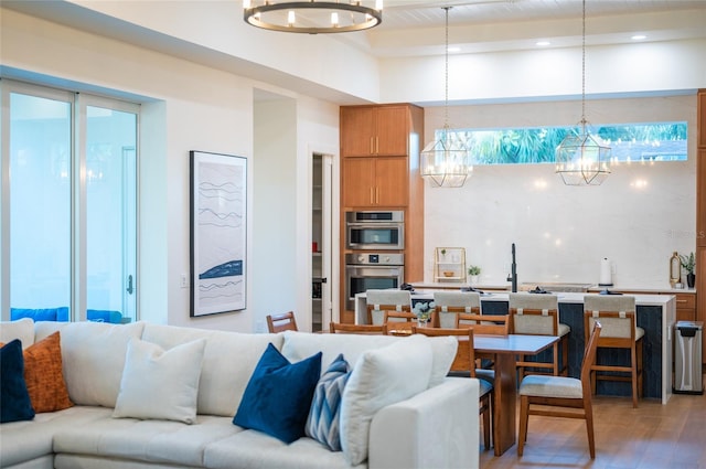 living room featuring beamed ceiling, wood-type flooring, and a chandelier