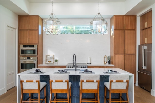 kitchen with stainless steel appliances, hanging light fixtures, sink, and a breakfast bar area