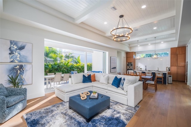 living room featuring an inviting chandelier, hardwood / wood-style floors, and beamed ceiling