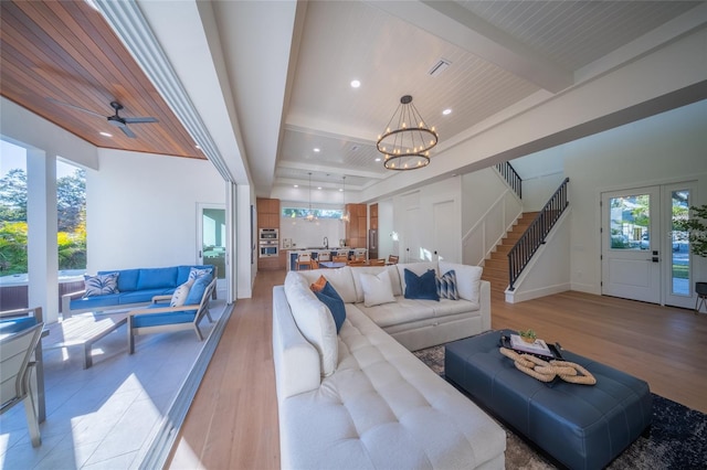 living room with a healthy amount of sunlight, beam ceiling, and light hardwood / wood-style floors