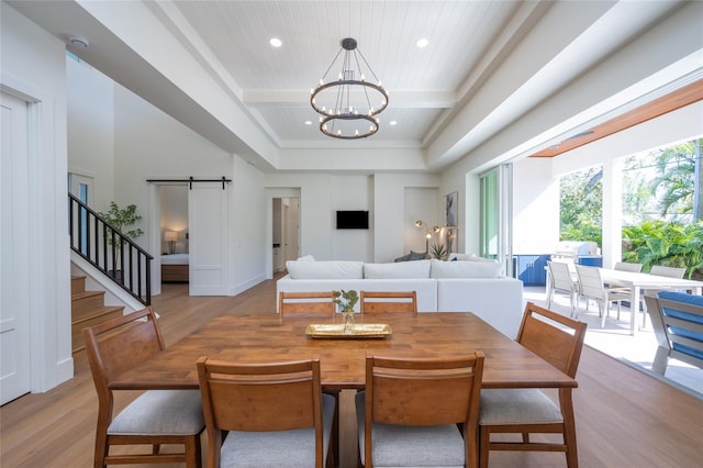 dining space with light hardwood / wood-style flooring, beam ceiling, coffered ceiling, a notable chandelier, and a barn door