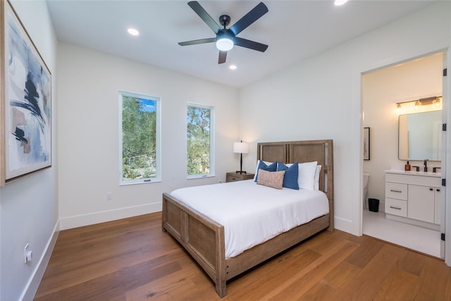 bedroom featuring connected bathroom, wood-type flooring, sink, and ceiling fan