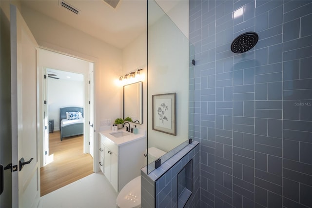 bathroom with hardwood / wood-style flooring, vanity, and tiled shower