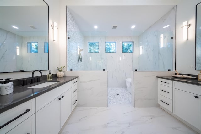 bathroom with a tile shower, vanity, and plenty of natural light