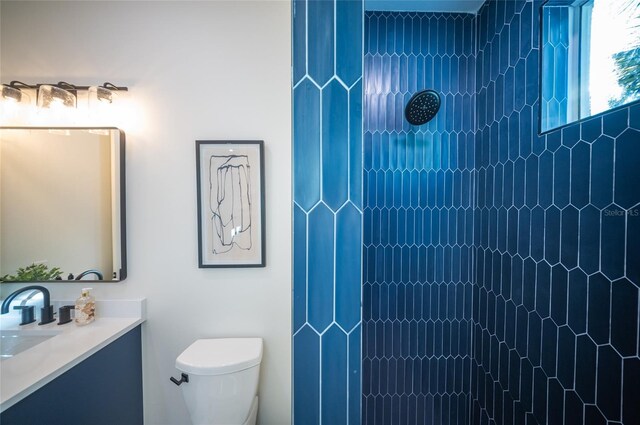 bathroom with vanity, tiled shower, and toilet