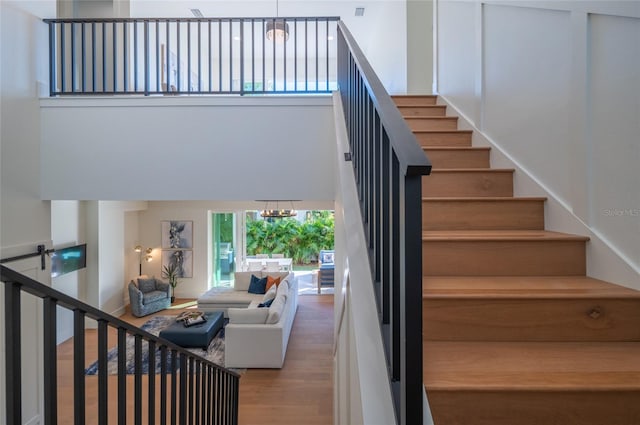 stairway featuring a notable chandelier, hardwood / wood-style floors, and a high ceiling