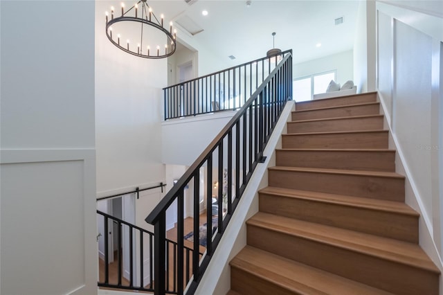 stairway with a towering ceiling and a chandelier