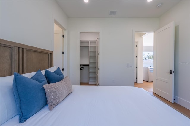 bedroom with hardwood / wood-style floors, a spacious closet, and a closet