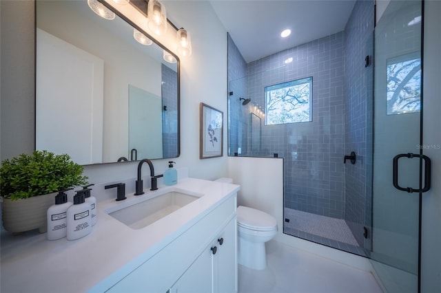 bathroom featuring vanity, a shower with shower door, and toilet