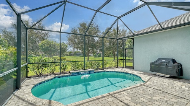 view of pool featuring glass enclosure, area for grilling, and a patio area