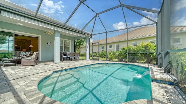 view of swimming pool with outdoor lounge area, pool water feature, ceiling fan, glass enclosure, and a patio