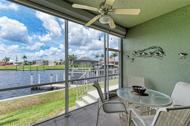 sunroom with a water view and ceiling fan