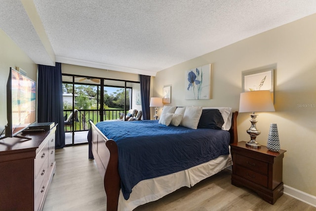 bedroom with access to exterior, baseboards, light wood finished floors, and a textured ceiling