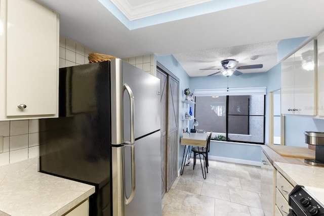 kitchen with light countertops, freestanding refrigerator, white cabinetry, ceiling fan, and range