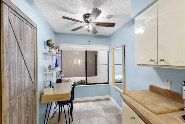 kitchen featuring a textured ceiling, a barn door, a ceiling fan, and baseboards